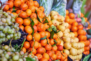 Orange tangerines with leaves and pears  lie on a counter in a fruit store top view. Mandarins in the market.