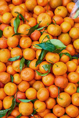 Orange tangerines with leaves lie on a counter in a store top view. Mandarins in the market.