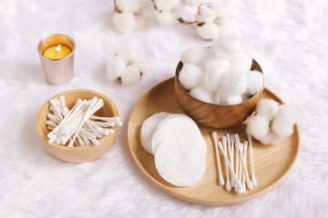 Fototapeta na wymiar Organic cotton facial pads, cotton balls and cotton buds for removal makeup on wooden tray with natural cotton flowers on white fur background, hygiene and healthy care lifestyle
