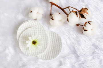 Obraz na płótnie Canvas Cotton facial pads for removal makeup with natural cotton flowers on white fur background, hygiene and healthy care lifestyle
