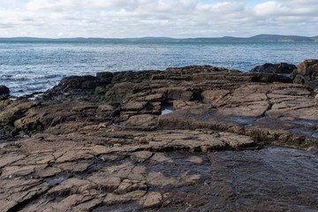 Landscape of brown horizontal rock formations and the Pacific Ocean at Washington Park in Anacortes, Washington