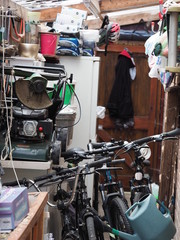 a shed with a jumble of things inside, including three bicycles 