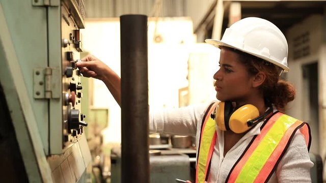 Industry maintenance engineer woman dark skin wearing uniform and safety helmet under inspection and checking production process on factory station by tablet. Industry, Engineer, construction concept.