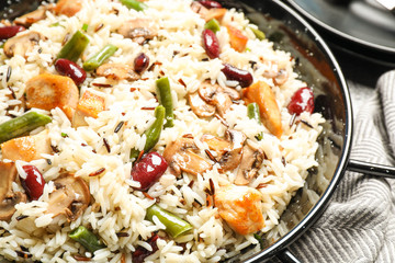 Delicious rice pilaf with chicken and vegetables in pan, closeup