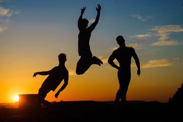 Fototapeta premium Group Of Happy Young People Jumping On The roof with sunset on background 