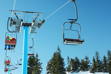 People using chairlift at mountain ski resort. Winter vacation