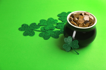Fototapeta na wymiar Pot of gold coins and clover leaves on green background, space for text. St. Patrick's Day celebration