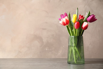 Beautiful spring tulips in vase on table against light background. Space for text