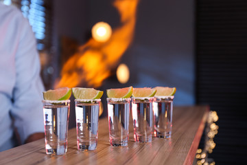 Mexican Tequila shots with lime slices on bar counter