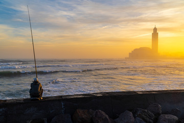 Fisher men sits on the edge in front of Hassan II Mosque at sunrise - Casablanca, Morocco