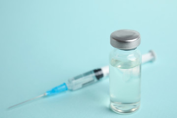 Vial and syringe on turquoise  background, space for text. Vaccination and immunization