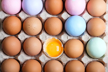 Paper craft tray with natural organic eggs and handmade painted with one yolk in a shall. Natural background.