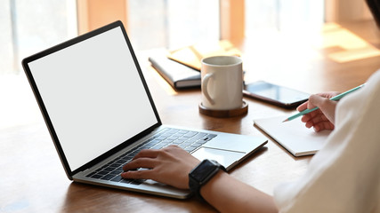 Cropped image of secretary woman's hands while typing on white blank screen computer laptop and...