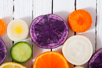 sliced fruits and vegetables on white wood table background