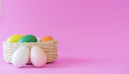 close up front view group of Easter eggs in basket over pink pastel color background with rolling ribbon and copy space for design in festival concept