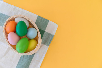 close up top view group of Easter eggs in basket over tablecloth on yellow pastel color background with copy space for design in festival concept