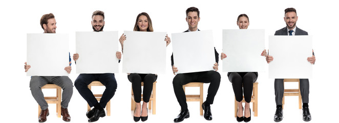 6 businessmen holding blank billboard while sitting on chairs