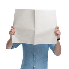 Young casual man covering his face with a newspaper