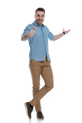 Happy casual man presenting and giving thumbs up