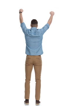 Rear view of casual man celebrating while wearing blue shirt