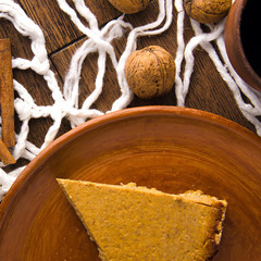 Obraz premium Homemade pumpkin pie with nuts and cinnamon on wooden rustic background top view. cake on a clay plate