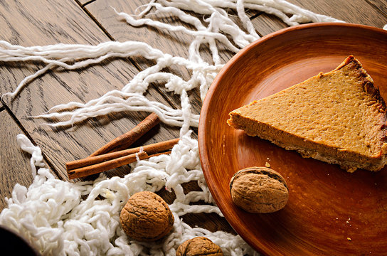 Homemade pumpkin pie with nuts and cinnamon on wooden rustic background top view. cake on a clay plate