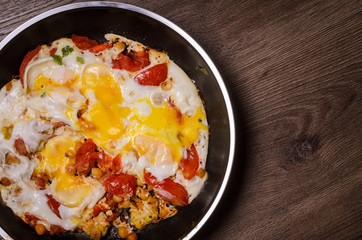 Fried eggs in a frying pan for breakfast on a wood background