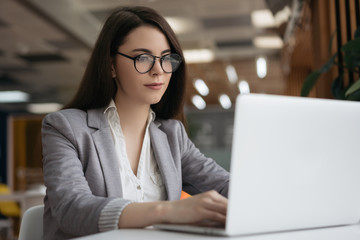 Pensive businesswoman using laptop computer, watching online training courses, working in office....