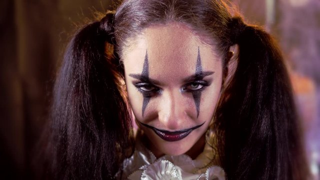 Portrait of a woman. A clown with a smile in corset with a white collar on the neck. Model with makeup for Halloween. The woman bats her eyelashes.