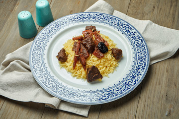 Light, diet pilaf with beef and carrots on a white plate on a wooden background. Top view with copy space for text. Traditional oriental cuisine