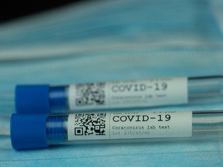 Test tube sample COVID-19 test on background from face masks