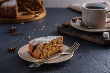 Fragrant and tasty carrot cake with a crispy crust on a plate with a cup of coffee on a dark background
