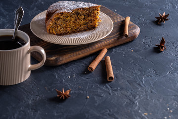 Fragrant and tasty carrot cake with a crispy crust on a plate with a cup of coffee on a dark background