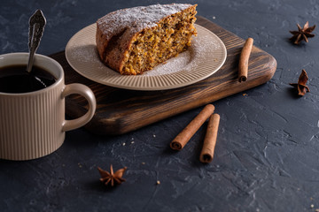 Fragrant and tasty carrot cake with a crispy crust on a plate with a cup of coffee on a dark background