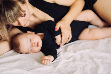 mother and baby in black sleeping together on bed