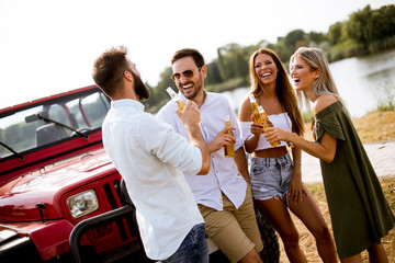 Group of young people drinking and having fun by car outdoor