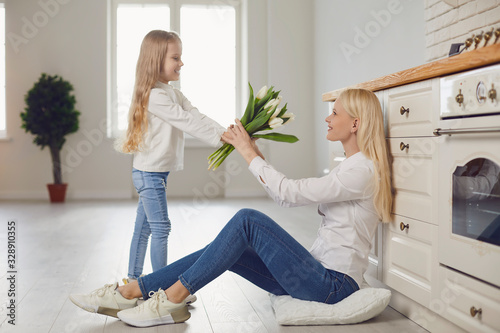 Happy mother's day. Daughter gives flowers tulips to mother at home.