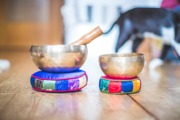 Tibetan singing bowl on a rustic wooden floor. Instrument for mediation and message. Cat in the background.