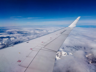 Obraz premium Airplane flight. Wing of an airplane flying above mountains and clouds