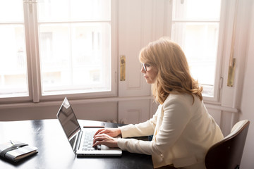 Businesswoman sitting at desk and working on her laptop