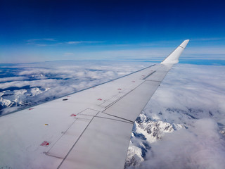 Airplane flight. Wing of an airplane flying above mountains and clouds