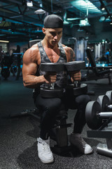 Fototapeta na wymiar Fit young man in sportswear focused on lifting a dumbbell during an exercise class in a gym