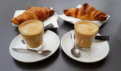 Glass Cups of Coffee with Fresh Croissants on a Black Table 