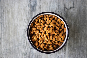 Dry cat food in a white bowl on gray background.