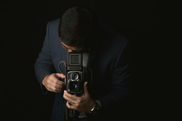 Fototapeta premium Professional photographer with vintage medium format camera, Portrait of a man in suit with twin lens classic camera in photography studio, Vintage camera collecting is trendy lifestyle.
