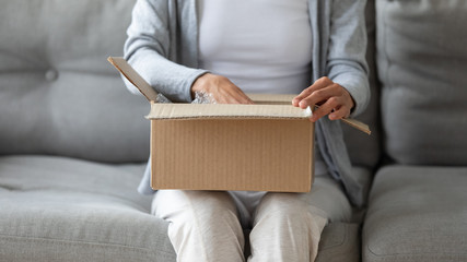 Close up of young woman open cardboard box order shopping online in Internet, female client or...