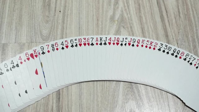 hand is playing a tape of playing cards on a wooden surface
