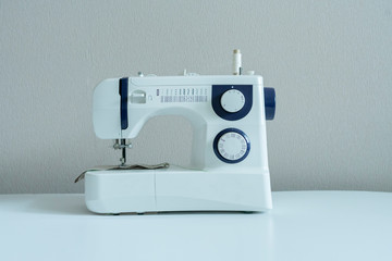 a simple sewing machine on the shelf against the wall isolated, home supplies