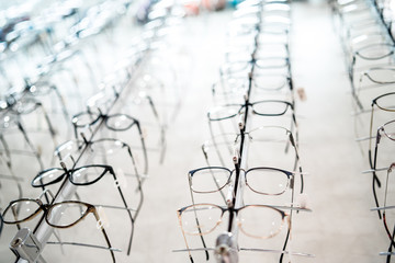 Exhibition of glasses at shelves. Fashionable spectacles shown on a wall at the optical shop. Closeup.