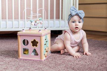 Cute baby girl playing with wooden activity toy.